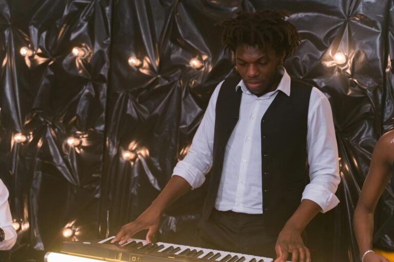 An adult male pianist performs at a keyboard with an elegant light-studded backdrop, exuding a serene atmosphere.